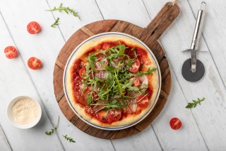 Pizza con jamón, rúcula y tomates cherry